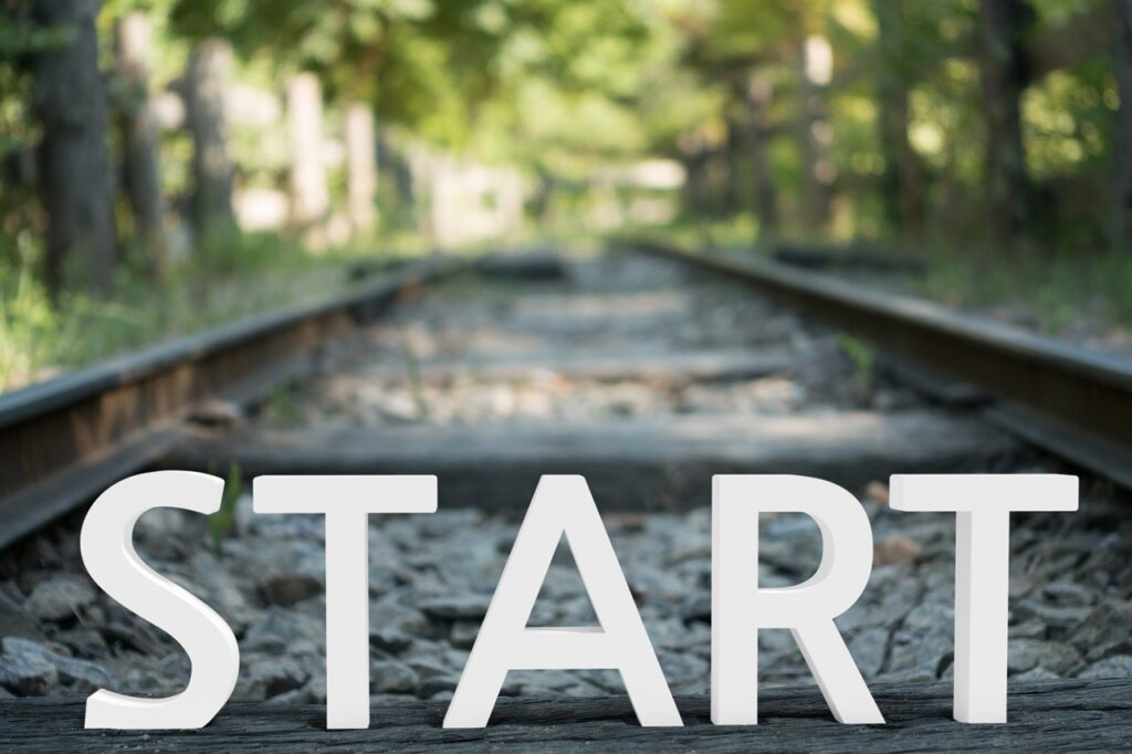 The word "start" hovering in front of train tracks in a forest.